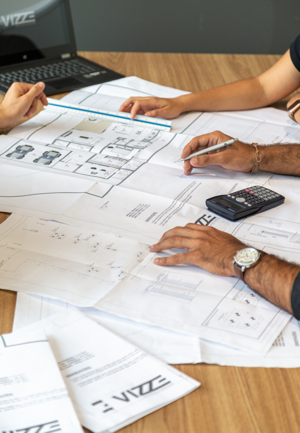 Tres personas revisando planos sobre una mesa de madera.