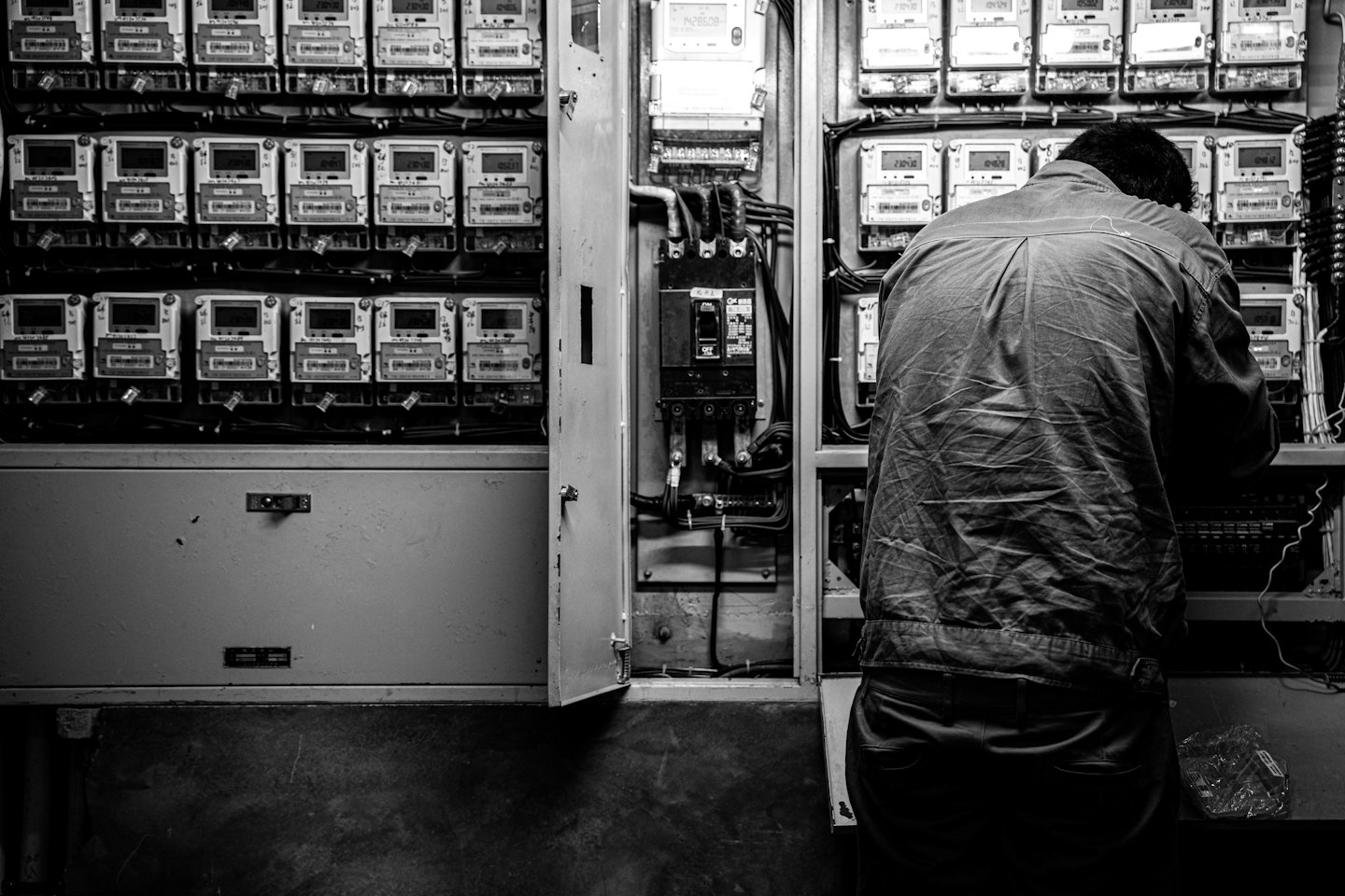 Persona trabajando en un panel eléctrico abierto con cableado complejo.